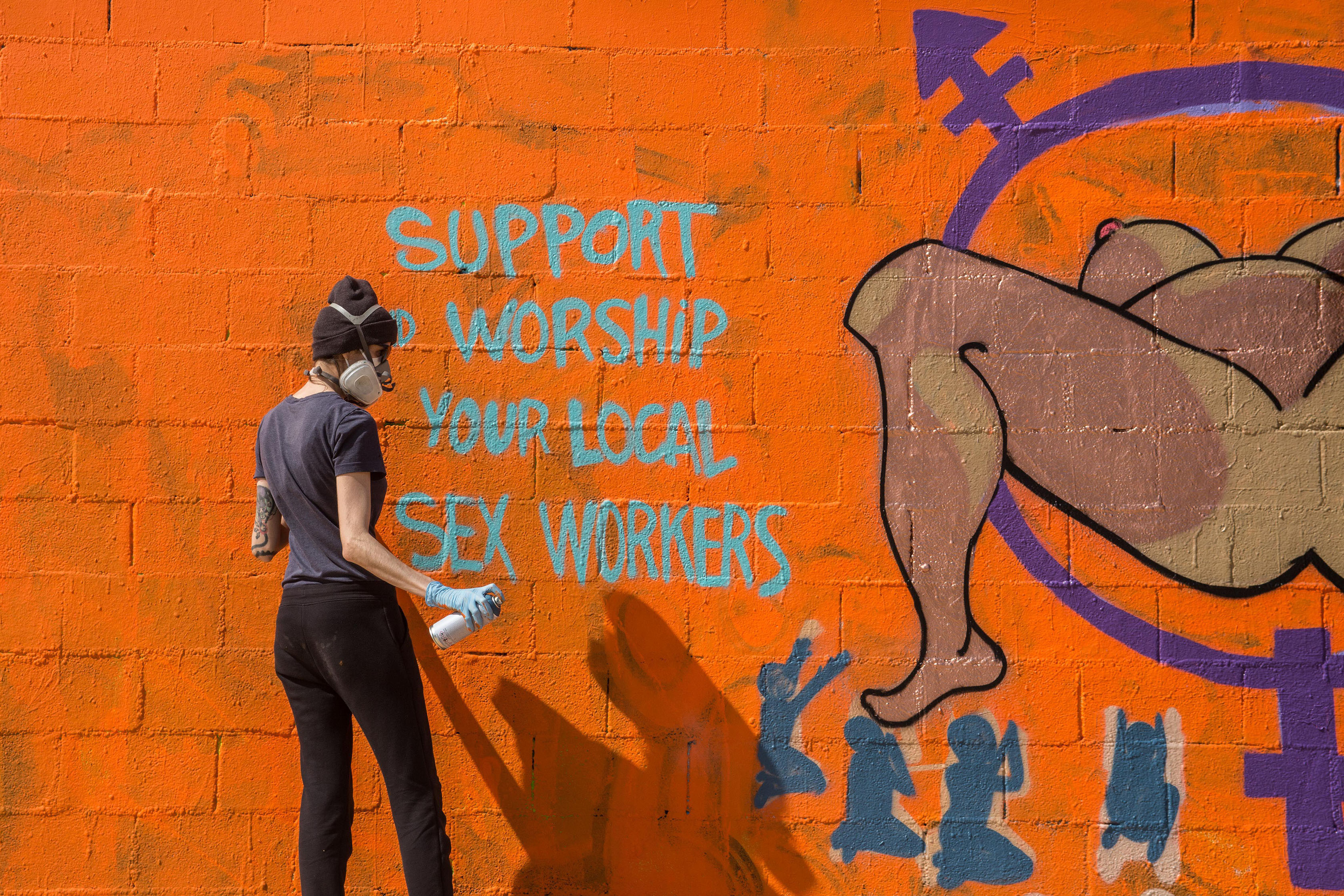 female graffiti artist in front of bricked wall