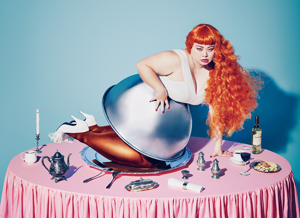 Red haired, curvy woman in a plate on a set table