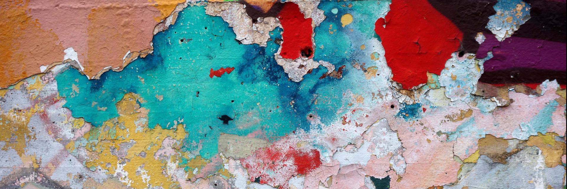 Wall with colorful blotches of paint and falling apart