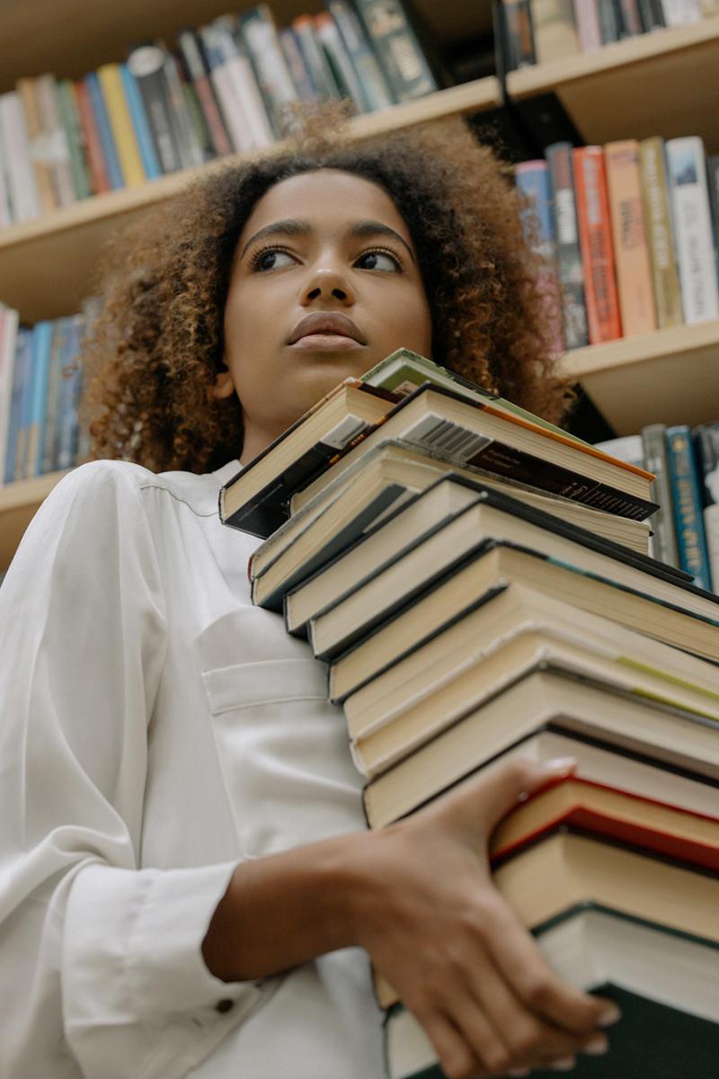 Girl college students holding a pile of books