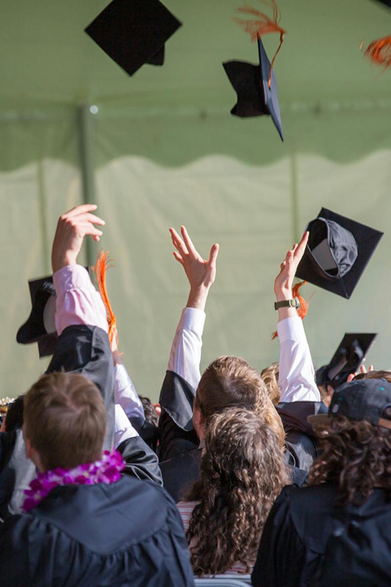 Graduated student throwing their caps up at commencement